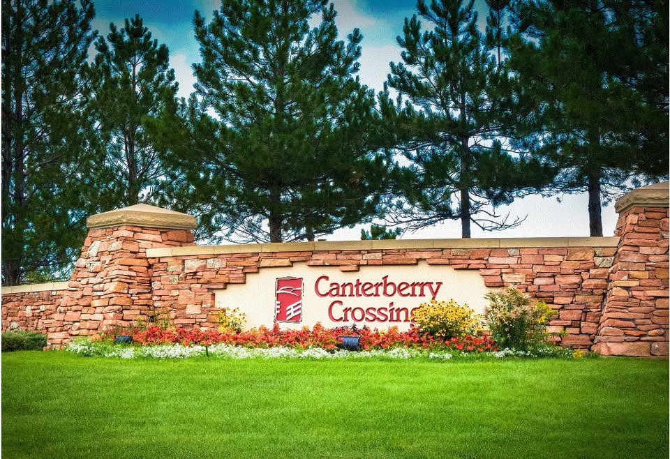 Stone entrance sign for Canterberry Crossing in Parker, Colorado surrounded by greenery and flowers