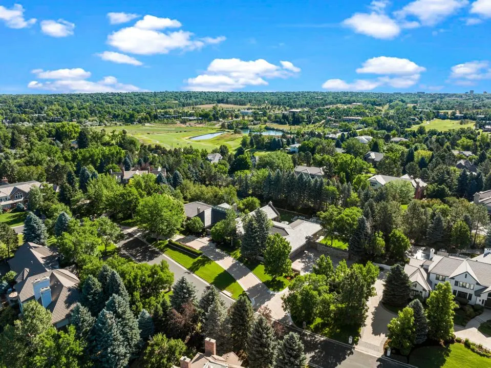 Aerial view of Cherry Hills Village with lush greenery and residential homes under a blue sky.