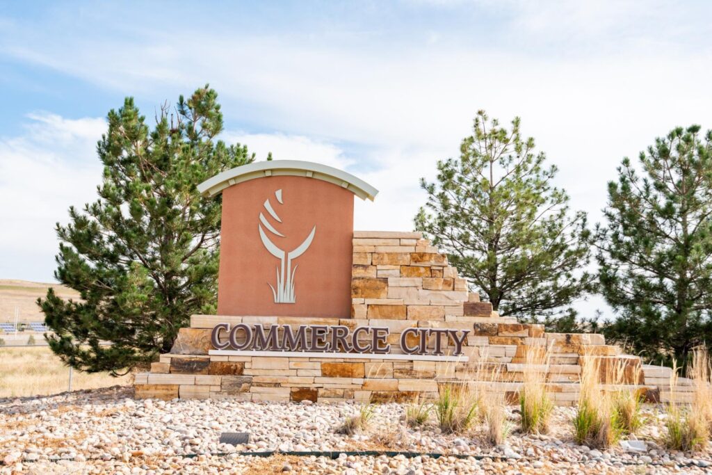 Commerce City welcome sign with stone background and trees