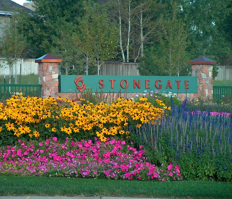Entrance sign of Stonegate community with colorful flowers and greenery