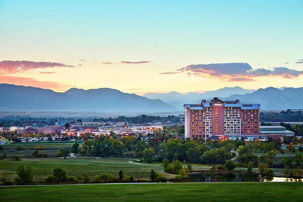 Scenic view of Westminster, Colorado at sunset with mountains and buildings in the background.